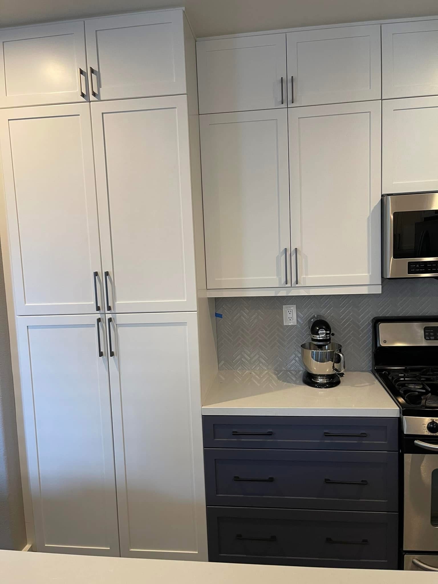 Modern kitchen with white and black cabinetry, stainless steel appliances, and herringbone backsplash