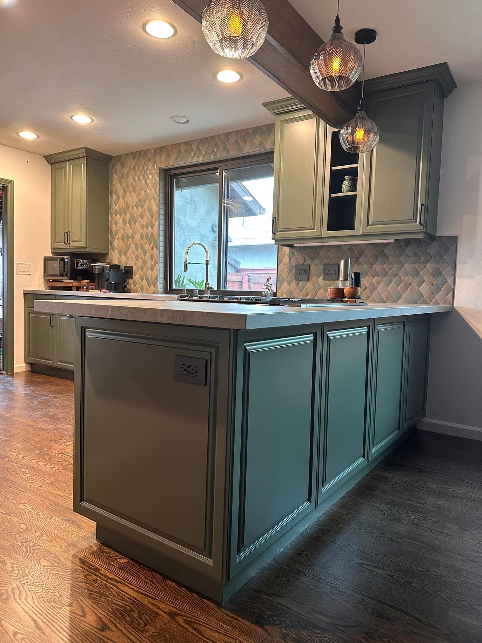 Modern kitchen with teal island, cream cabinets, quilted backsplash, pendant lights, and stainless steel appliances