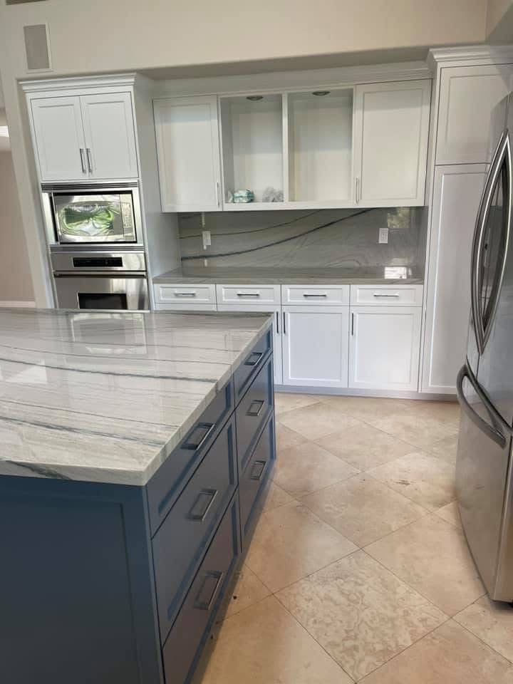 Modern kitchen with white cabinetry, gray island, stainless steel appliances and tile flooring