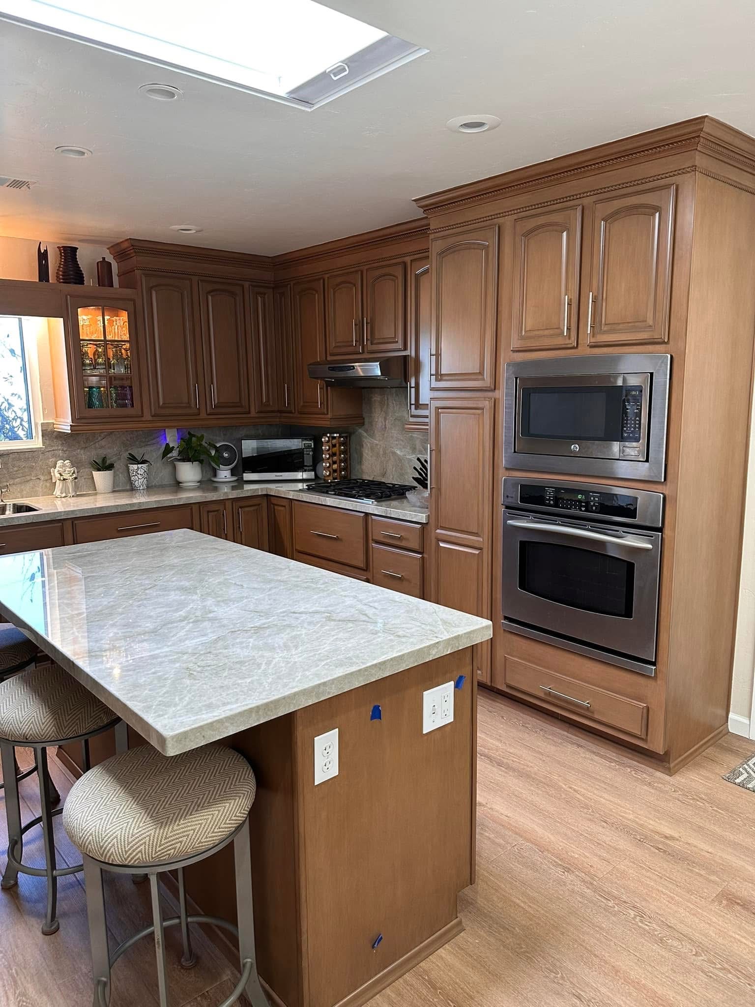 Luxury kitchen with wood cabinetry, marble countertops, stainless steel appliances and island seating