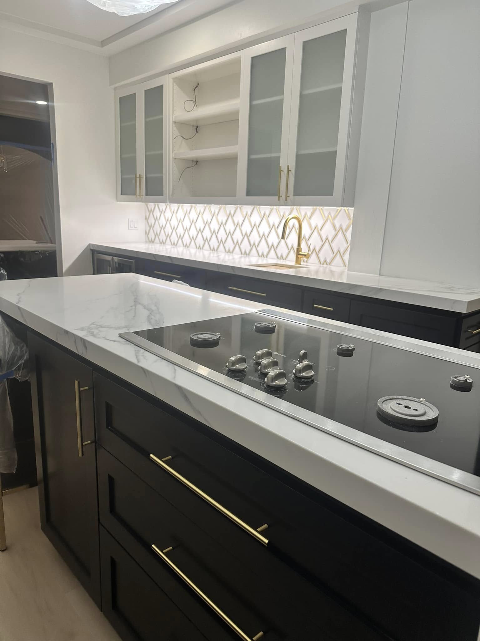 Modern kitchen with black lower cabinets, white marble countertops, and white upper cabinets with glass doors