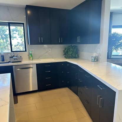 Modern kitchen with dark blue cabinets, white countertops, stainless steel appliances, and tile flooring